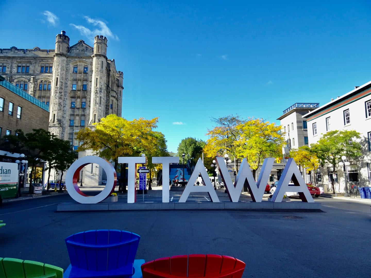 The OTTAWA sign in a streetscape with stone buildings, trees and blue sky