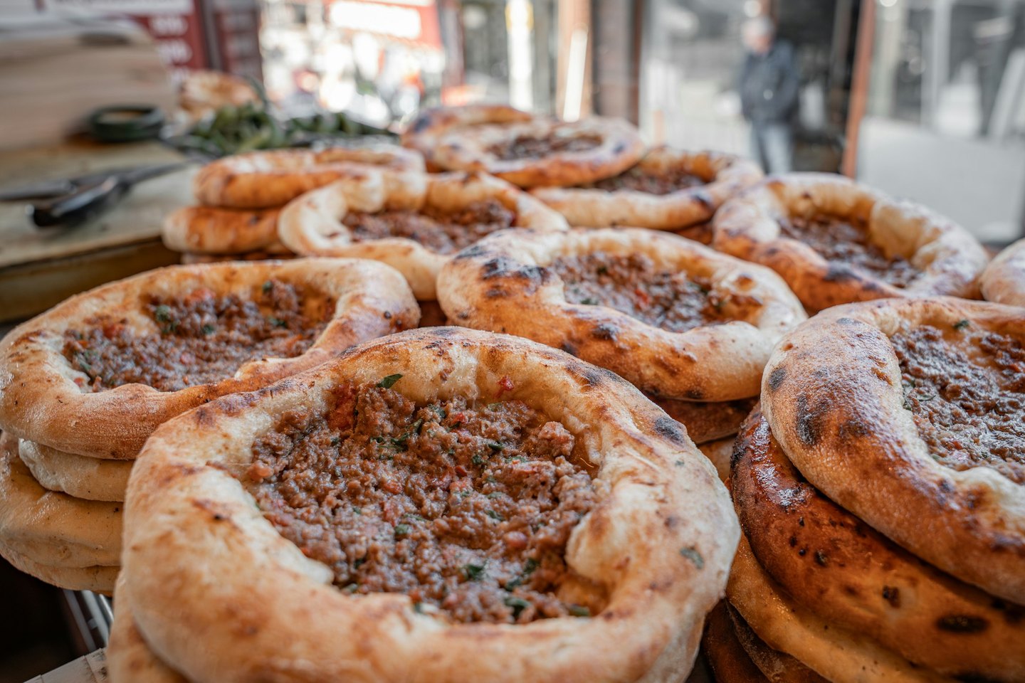 Freshly baked meat-topped flatbreads arranged on a counter.