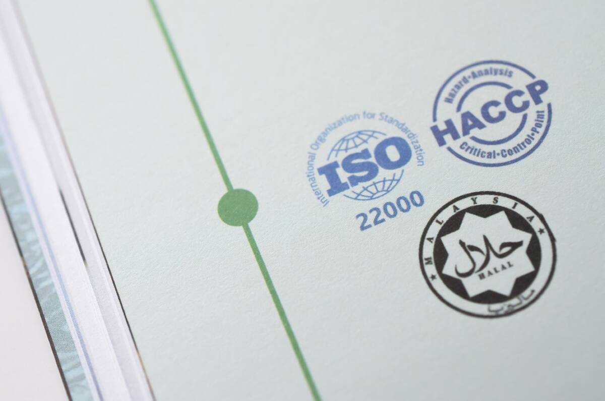 Close-up of a printed page showing ISO 22000, HACCP and a Malaysian halal certification stamp
