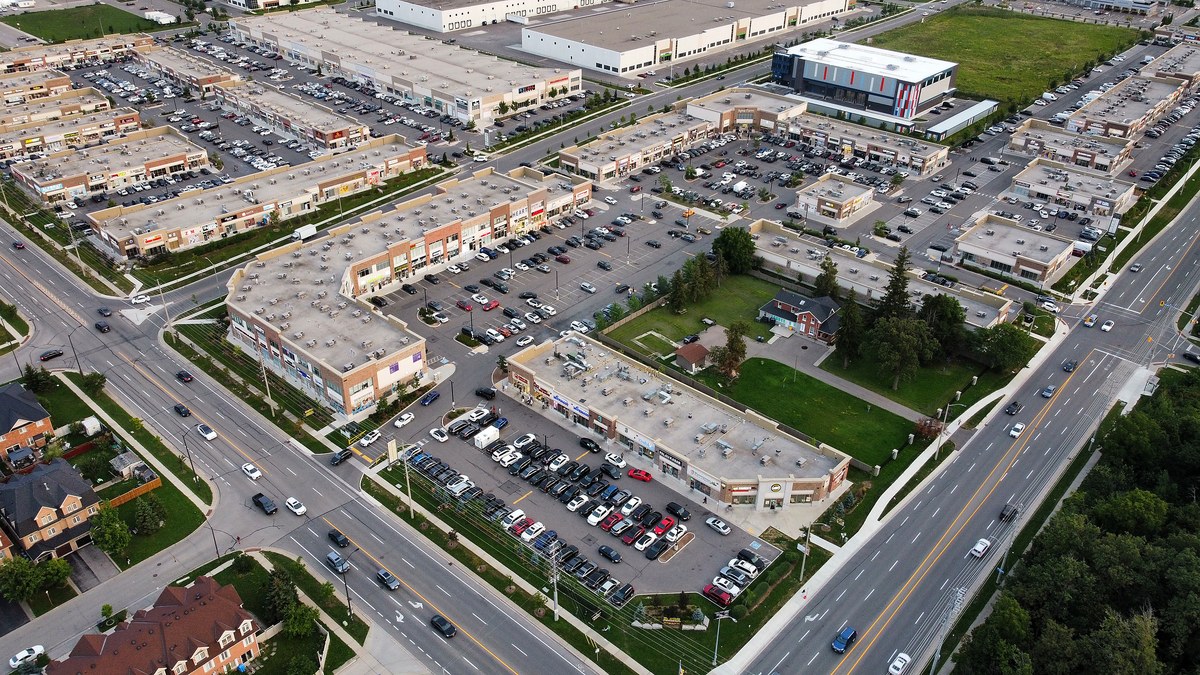 Aerial photograph of the Ridgeway Plaza retail cluster in Mississauga, showing several parallel strips of units separated by surface parking, with a road running through the middle